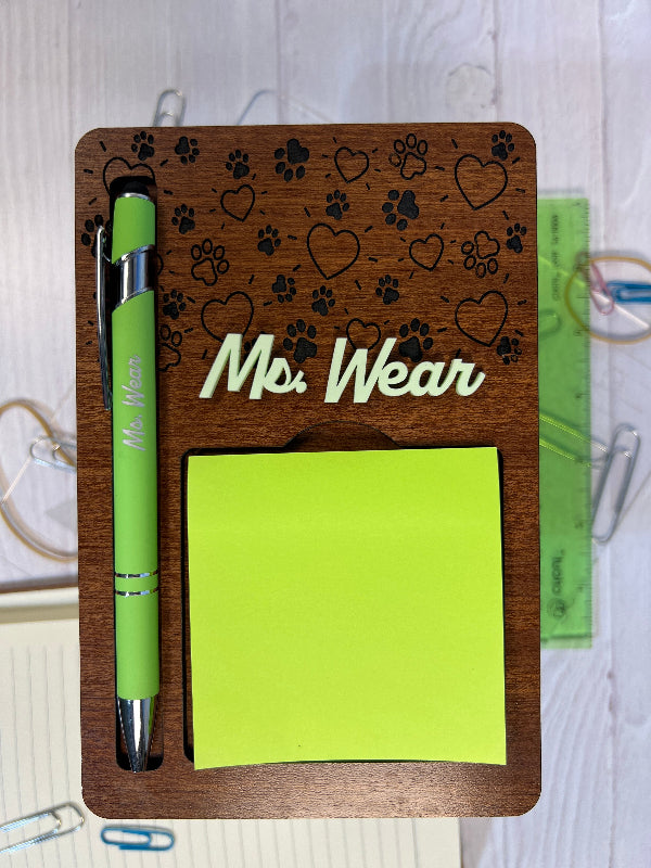 Wooden desk organizer with 'Ms. Wear' branding, green sticky notes, and pen on a white surface. From She Shed Designs