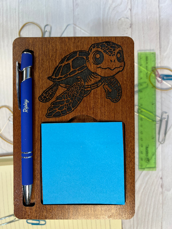 Wooden notepad holder with laser-cut Turtle design, blue sticky notes, and a blue pen on a white surface. Sticky Note Holder Personalized Pen