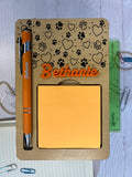 Holder with engraved pen and sticky notes on a textured surface. From She Shed Designs