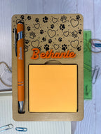 Holder with engraved pen and sticky notes on a textured surface. From She Shed Designs