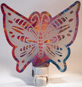 A Pink and blue paint pour acrylic nightlight in the shape of a butterfly, glowing with a warm light. From She Shed Designs.