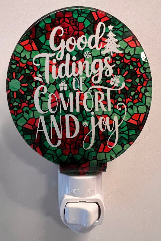 Handcrafted acrylic nightlight with a festive 'Good Tidings of Comfort and Joy' message, featuring red and green colors and a tree. From She Shed Designs.