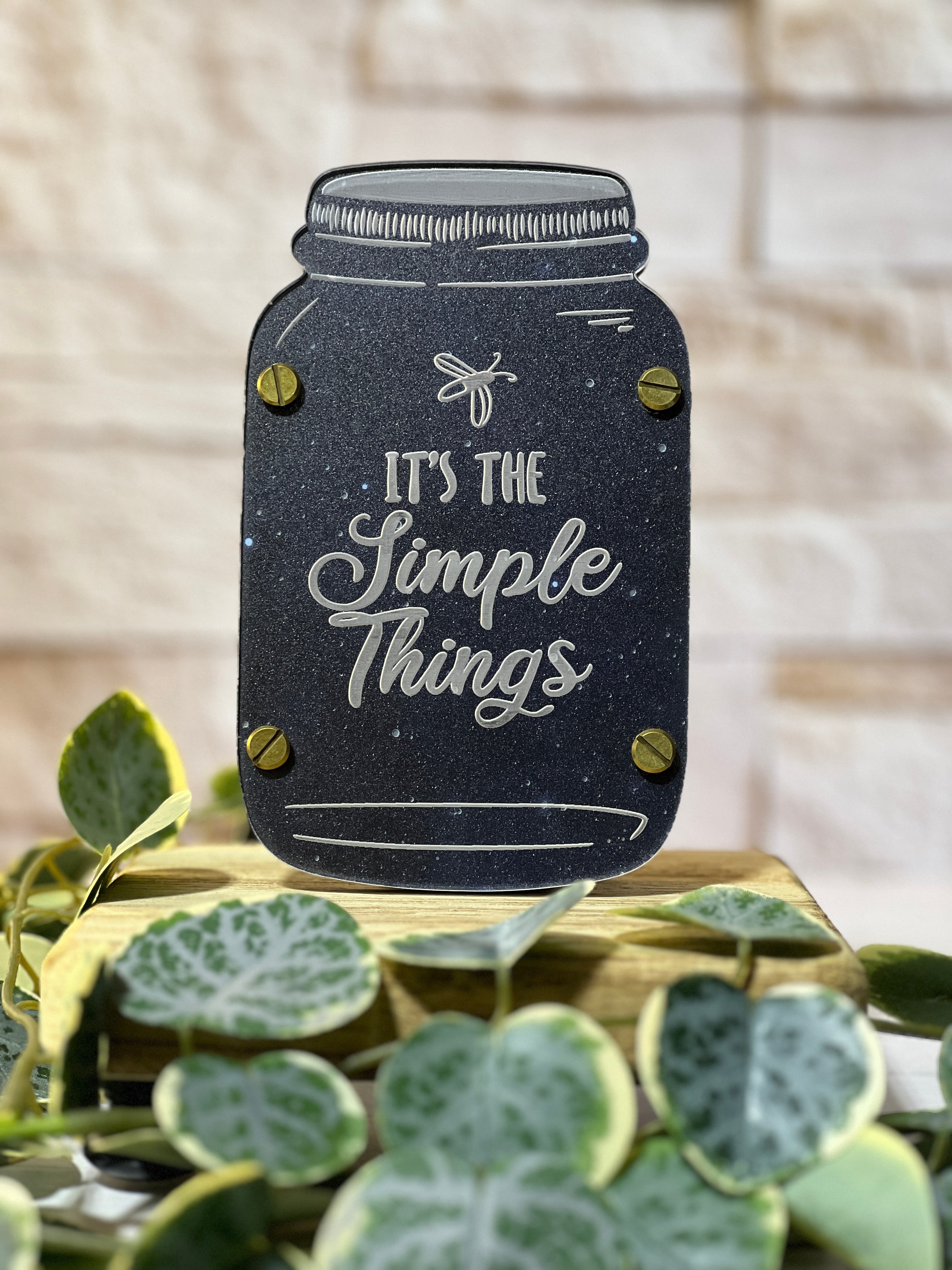 Decorative sign shaped like a mason jar with 'It's the Simple Things' text, surrounded by greenery. From She Shed Designs