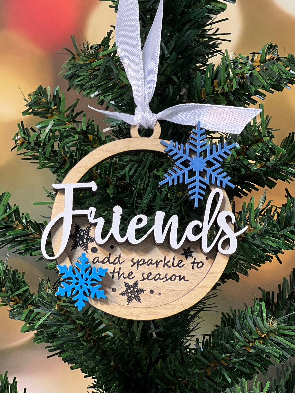 Decorative ornament with 'Friends add sparkle to the season' and snowflake design on a Christmas tree. From She Shed Designs
