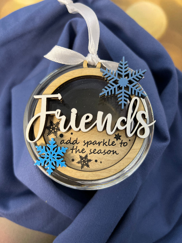 Decorative ornament with 'Friends add sparkle to the season' and snowflake design on a Christmas tree. From She Shed Designs