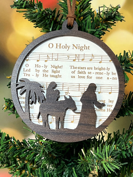 Decorative ornament with silhouette of Mary and Joseph on O Holy Night sheet music on a Christmas tree. From She Shed Designs