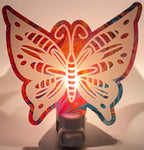 A Pink and blue paint pour acrylic nightlight in the shape of a butterfly, glowing with a warm light. From She Shed Designs.