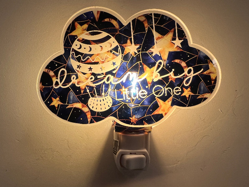Decorative night light with 'Dream Big Little One' text and celestial design on a wall. From She Shed Design.