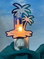 Decorative night light with palm tree and lighthouse design on a blue. From She Shed Designs. background