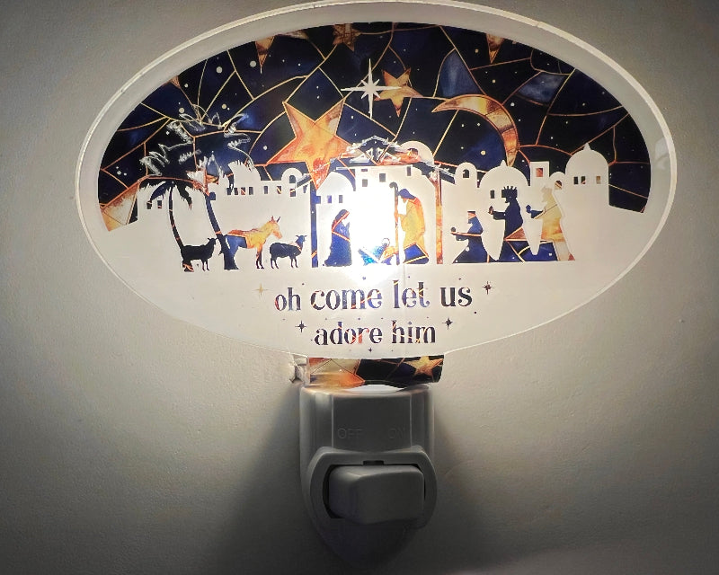 Decorative night light with nativity scene design and 'oh come let us adore him' text. From She Shed Design.