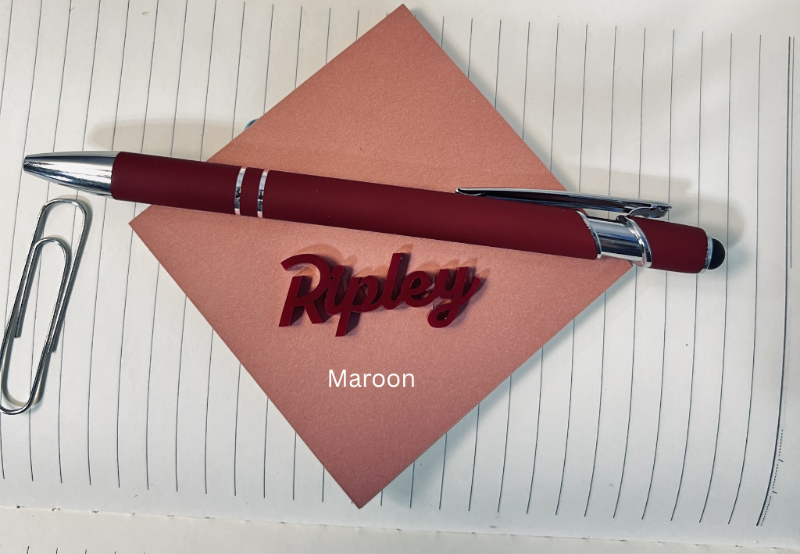 Maroon pen with silver clip on a pink paper with 'Ripley' branding, placed on lined paper. From She Shed Designs
