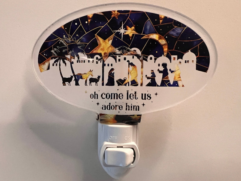 A handcrafted acrylic nightlight with a Christmas nativity scene design, featuring the text 'oh come let us adore him' on a dark background. From She Shed Design.