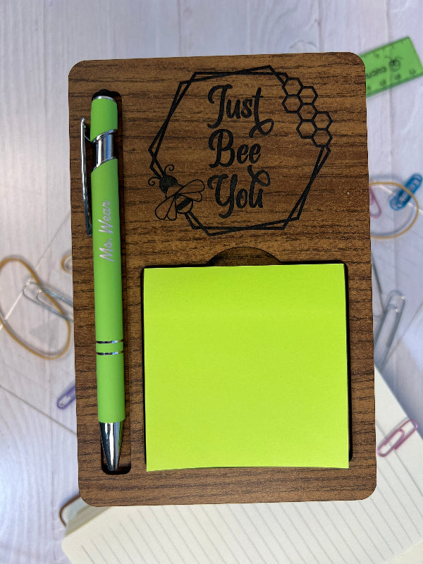 Wooden desk organizer with green pen and sticky notes on a white surface