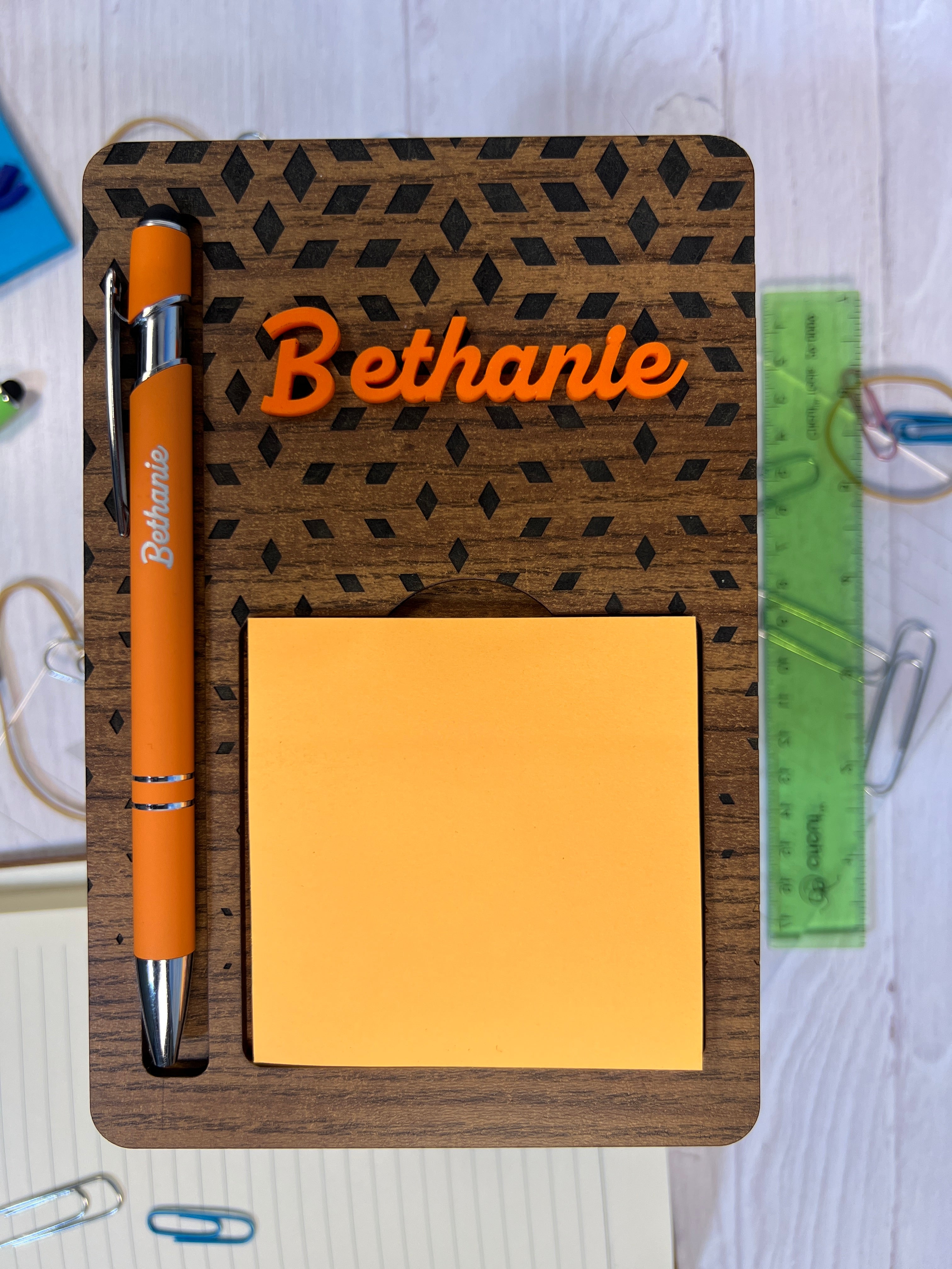 Holder, pen, and sticky notes with 'Bethanie' on a textured surface.