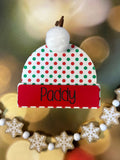 Decorative Christmas ornament with a red and green polka dot hat on a blurred festive background. From She Shed Designs