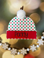 Decorative Christmas ornament with a red and green polka dot hat on a blurred festive background. From She Shed Designs