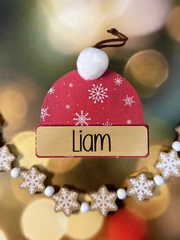 Personalized Beanie Christmas ornament Red with snowflakes and 'Liam' on a blurred festive background From She Shed Designs