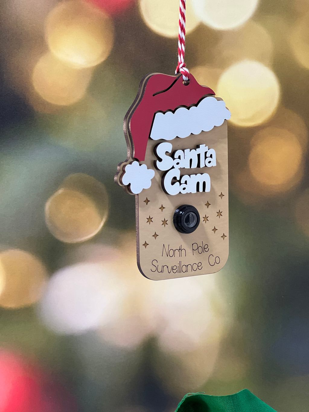Decorative tag with 'Santa's Cam' text on a blurred festive background From She Shed Designs