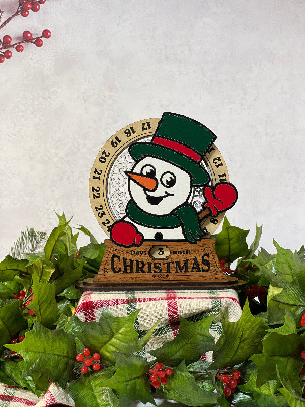 Christmas-themed Advent calendar stand with a Snowman design on a festive background. From She Shed Designs