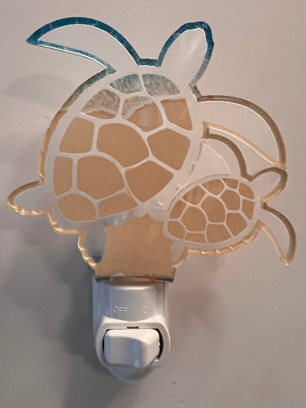 Handcrafted acrylic turtle-shaped nightlight glowing in a room, showing a mother turtle with a baby turtle design. From She Shed Design.