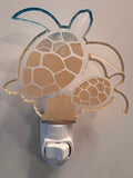 Handcrafted acrylic turtle-shaped nightlight glowing in a room, showing a mother turtle with a baby turtle design. From She Shed Design.